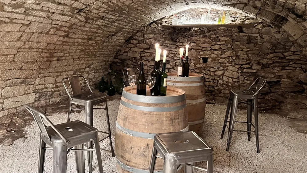 Vaulted stone cellar with a barrel, stools and candles