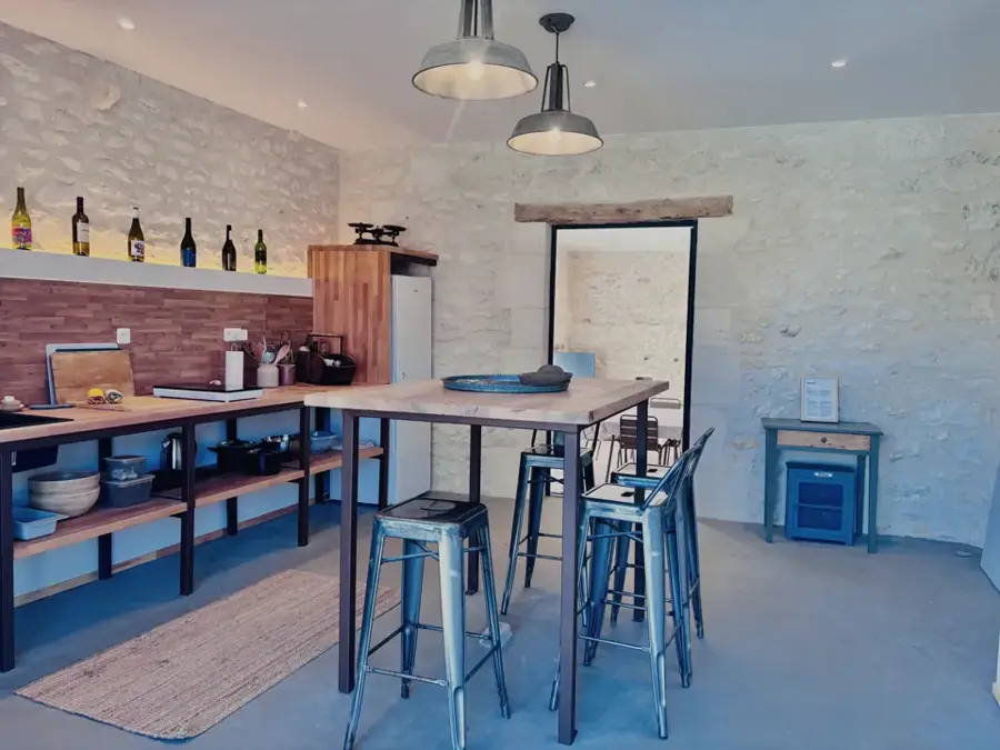 Summer kitchen with a large high table and a shelf of wine bottles