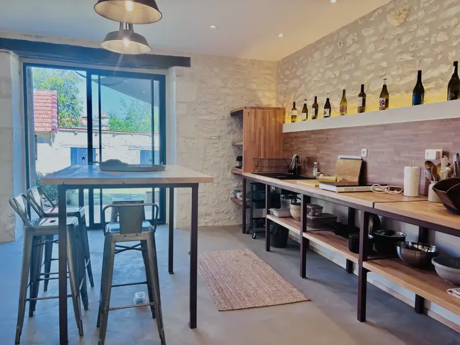 Summer kitchen in exposed stone with stools and high table