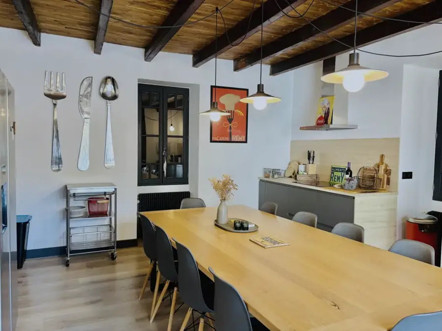 Kitchen and dining room with exposed beams and a long table